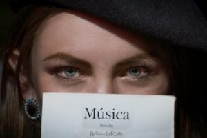 Close-up of a woman's eyes visible above a book titled Música. Intriguing gaze.